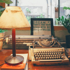 This photo shows a a typewriter surrounded by plants looking at a nearby apartment building